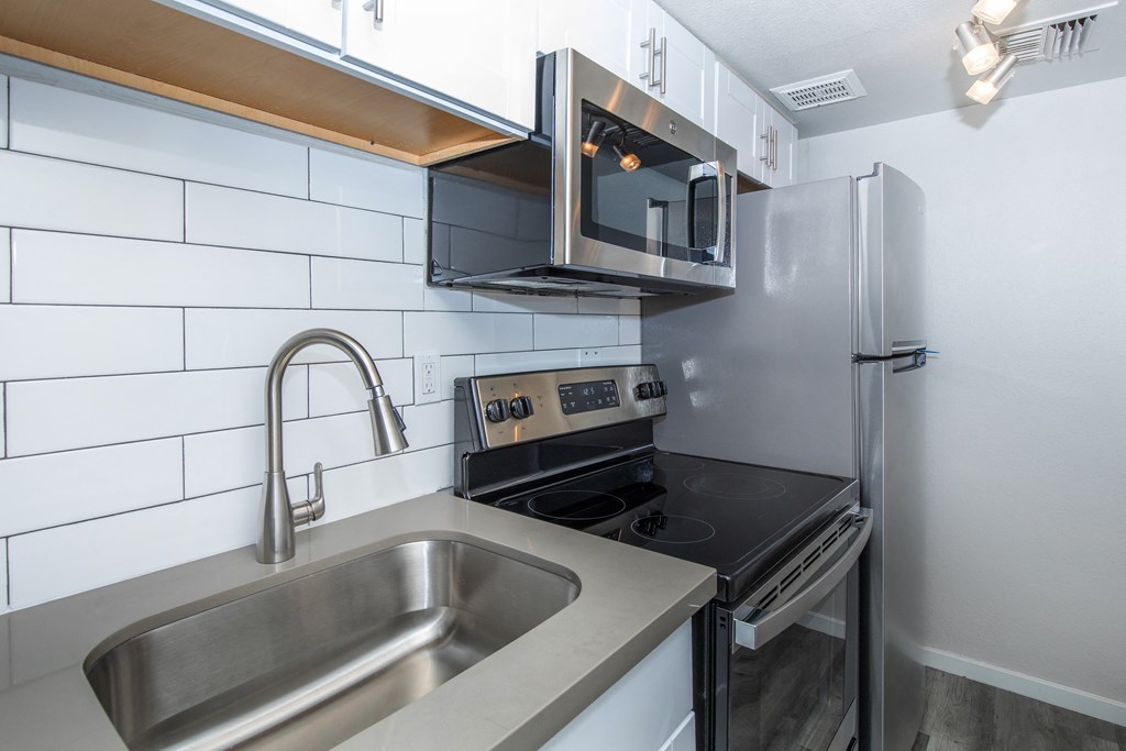 a kitchen with a sink stove microwave and refrigerator