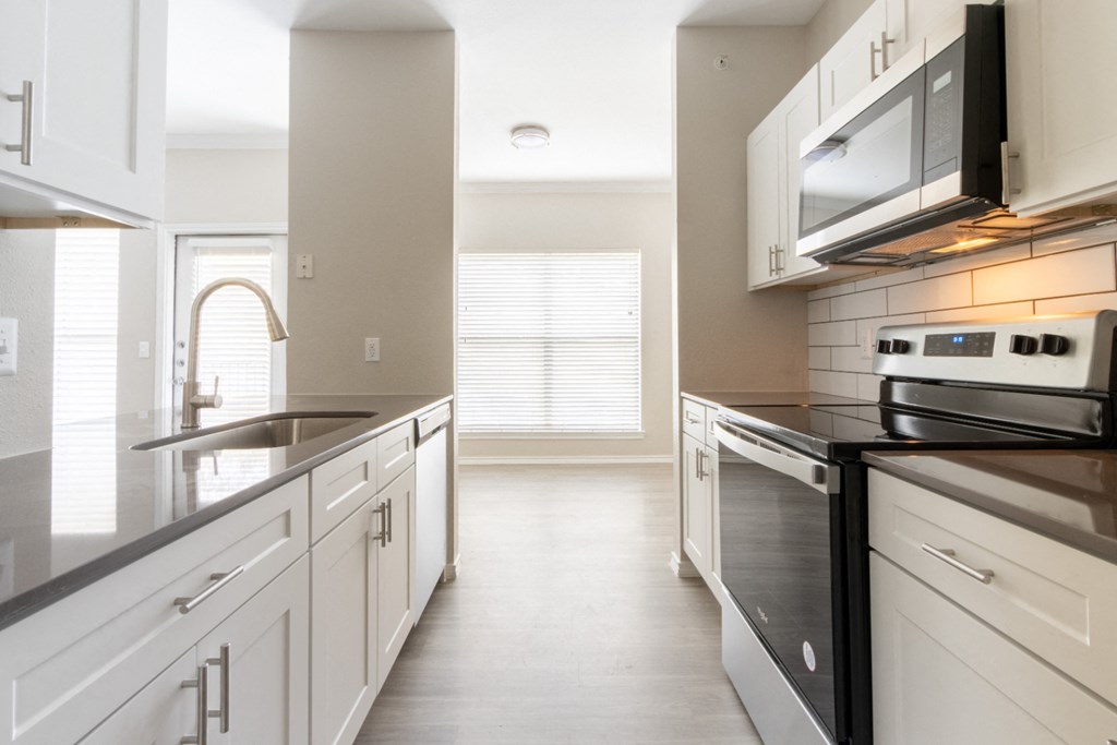 a kitchen with white cabinets and black countertops
