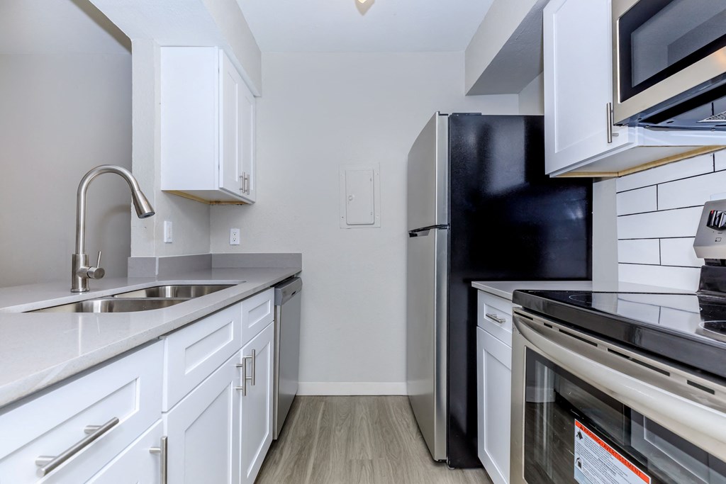 a kitchen with white cabinets and black appliances