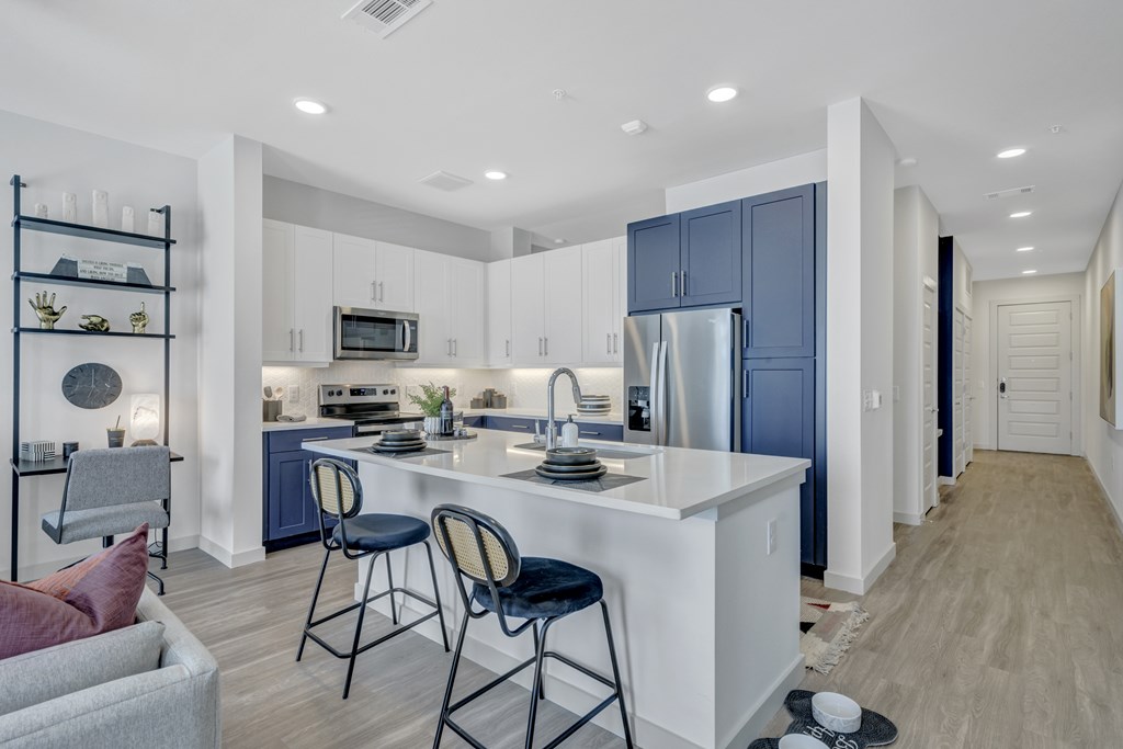 A kitchen with a white island and blue cabinets.