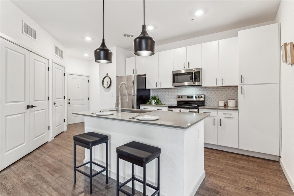 a large kitchen with white cabinets and a large island with three stools