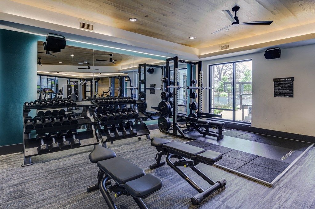 a gym with weights and cardio equipment and a window