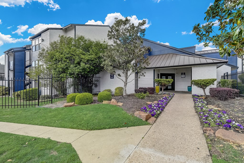 a white building with a gray roof and a sidewalk leading to the front door