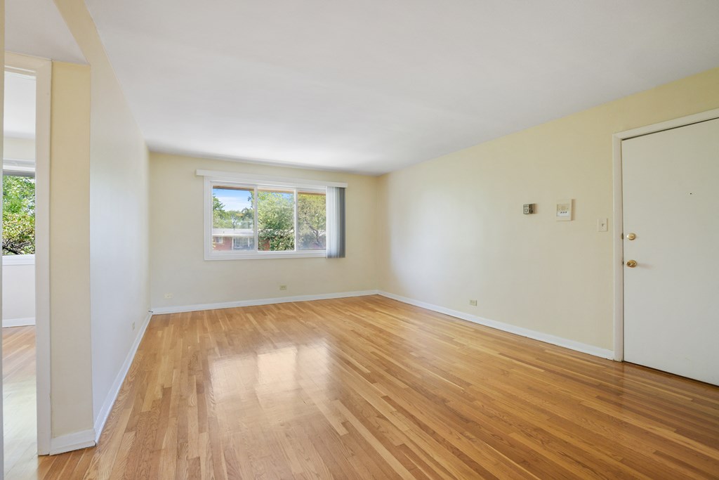 an empty living room with wooden floors and a window