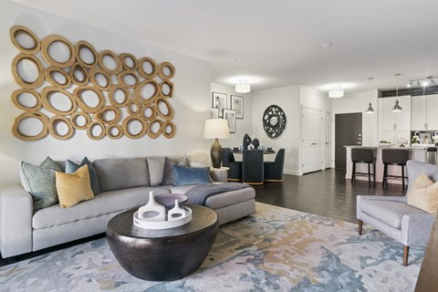 A modern living room with a grey couch and a large circular wall art.