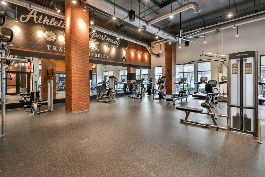 a gym with cardio equipment and weights on the floor