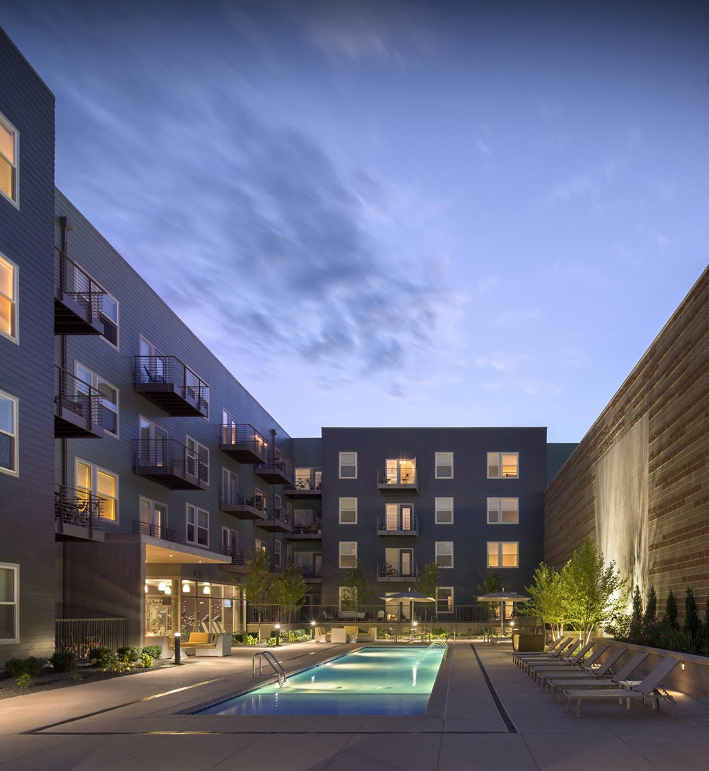a pool is lit up in the middle of an apartment complex at night