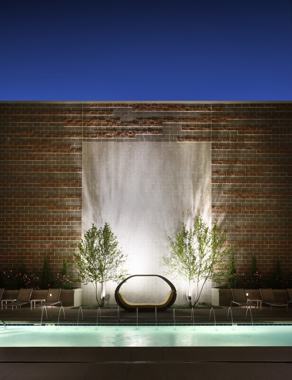 a pool with a chair in front of a brick wall