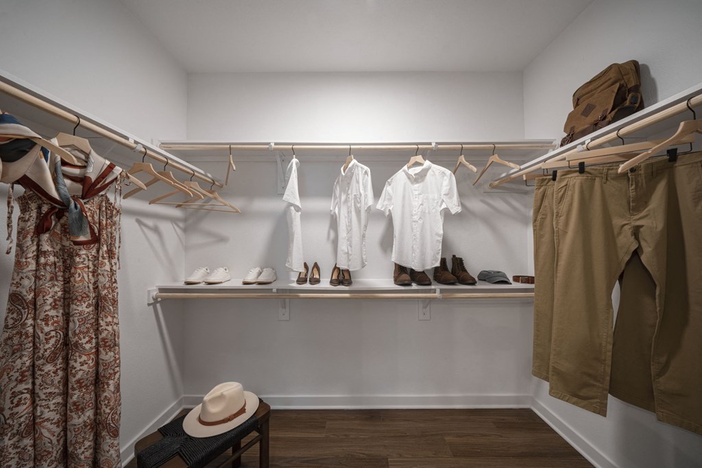 a walk in closet with white walls and wooden shelves