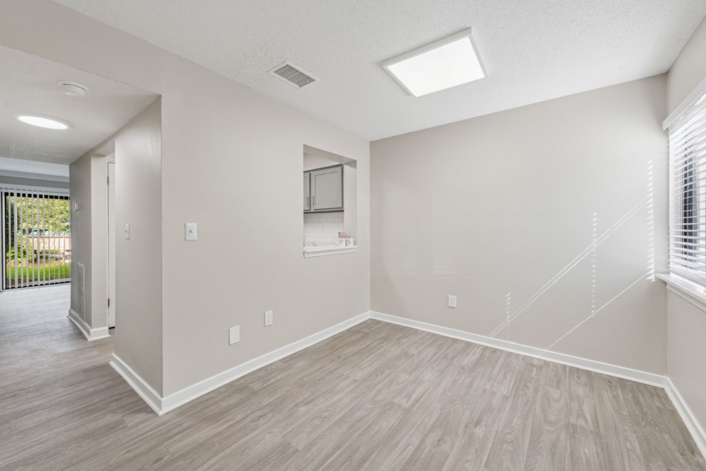 A spacious room with light wood flooring and white walls.