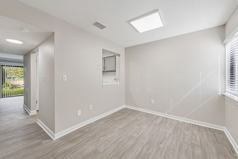 A spacious room with light wood flooring and white walls.