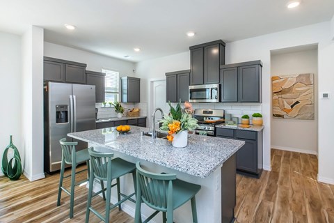 A kitchen with a granite countertop and green chairs.
