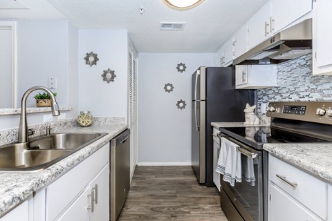 A kitchen with a black refrigerator and stove top oven.