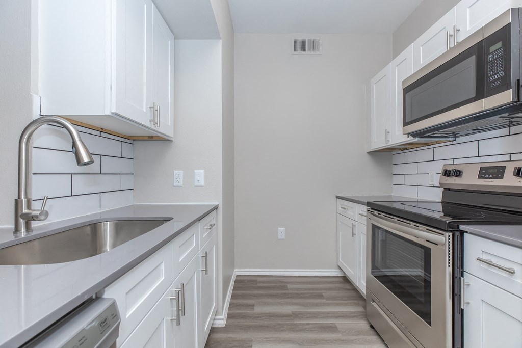 a kitchen with white cabinets and stainless steel appliances