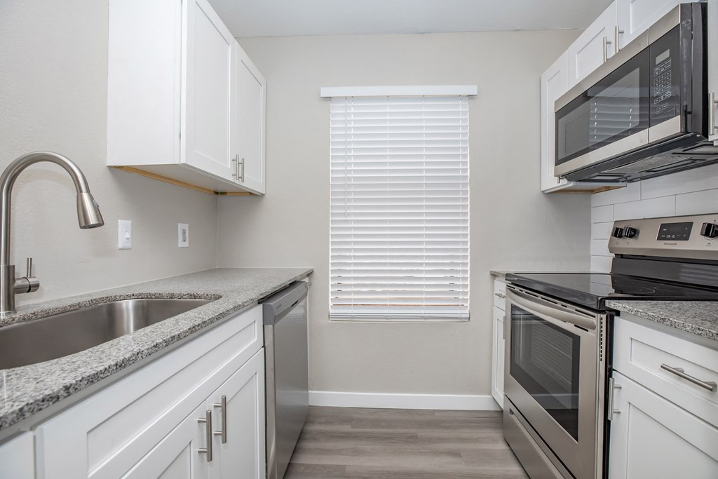 a kitchen with white cabinets and stainless steel appliances