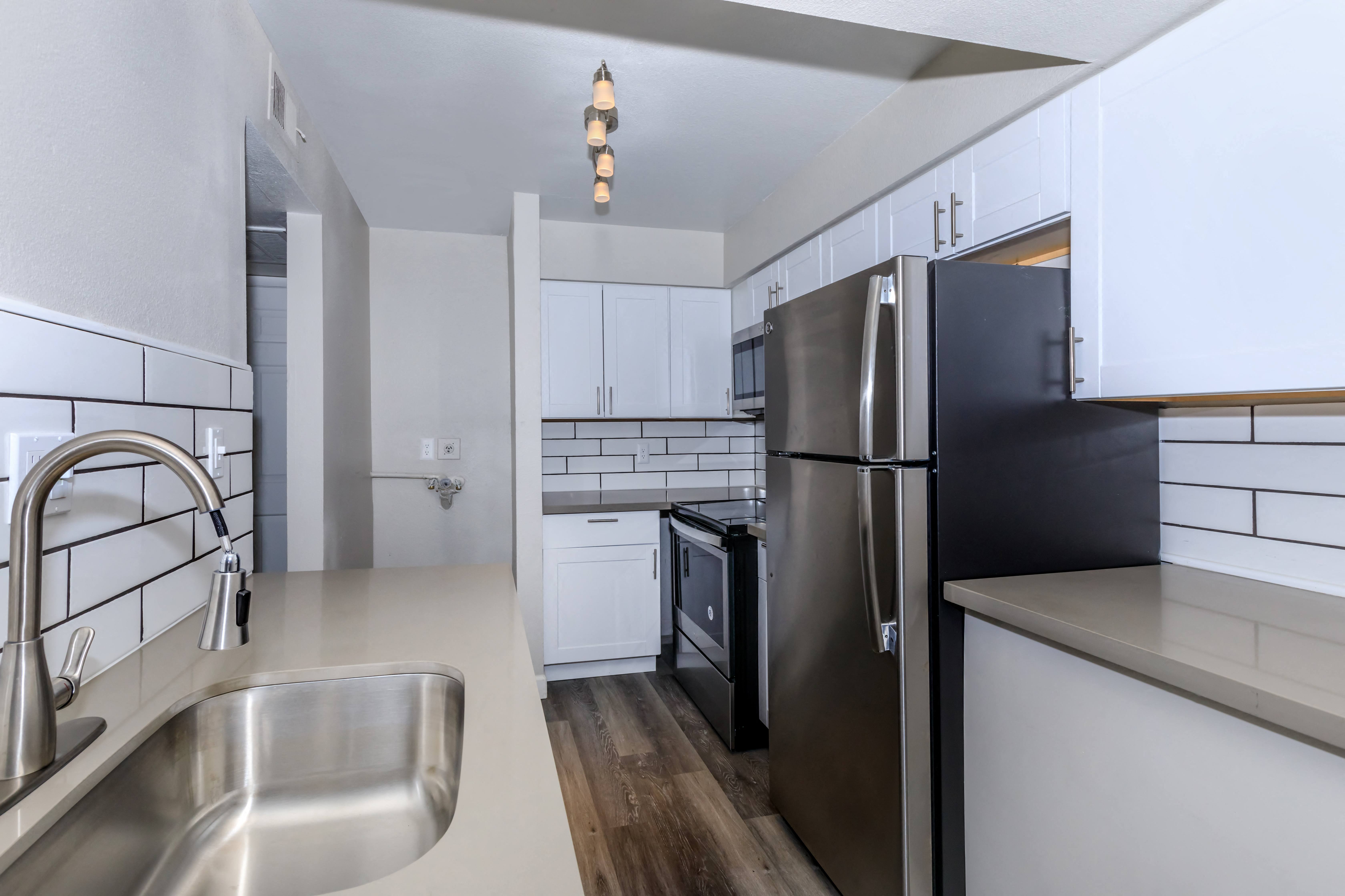 an empty kitchen with stainless steel appliances and white cabinets