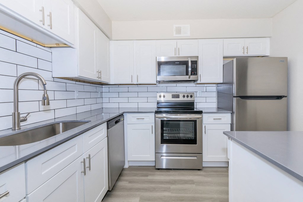 a white kitchen with stainless steel appliances and white cabinets