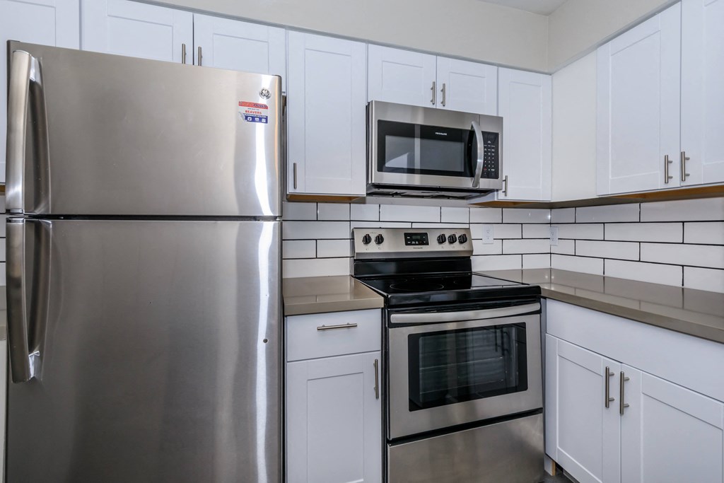 an empty kitchen with stainless steel appliances and white cabinets