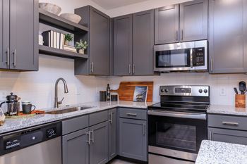 A kitchen with dark grey cabinets and stainless steel appliances.