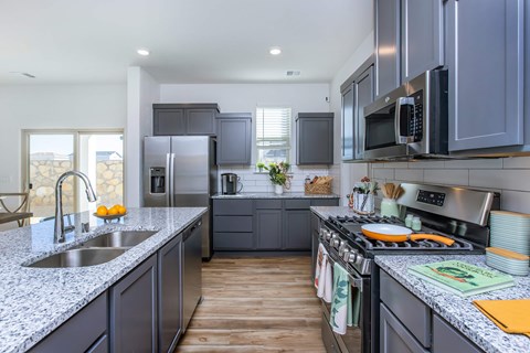 A modern kitchen with dark grey cabinets and stainless steel appliances.