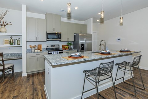 A kitchen with a white island and two chairs.