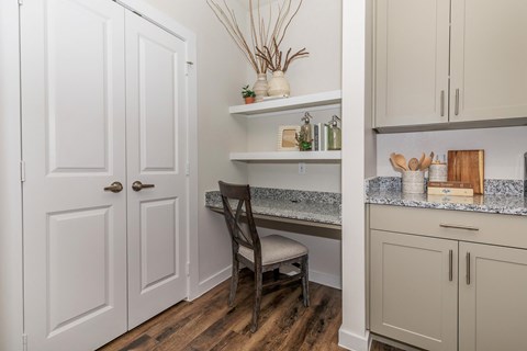 A kitchen with a white door, a chair, and a counter with a cutting board and utensils on it.