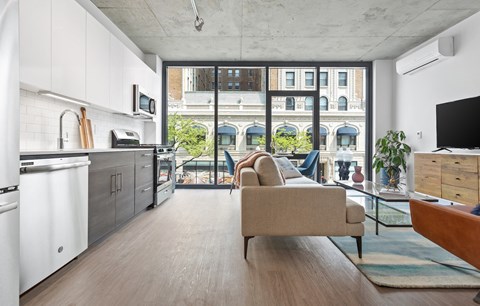 a living room with a couch and a kitchen and a balcony