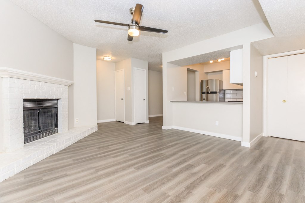 a living room with a fireplace and a kitchen in the background