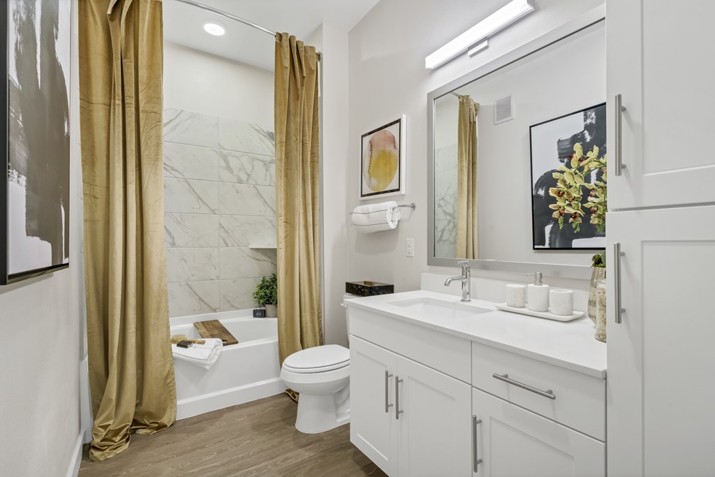 A bathroom with a white toilet, sink, and a marble wall.