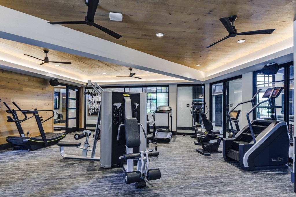a gym with treadmills and other exercise equipment in a building with glass doors