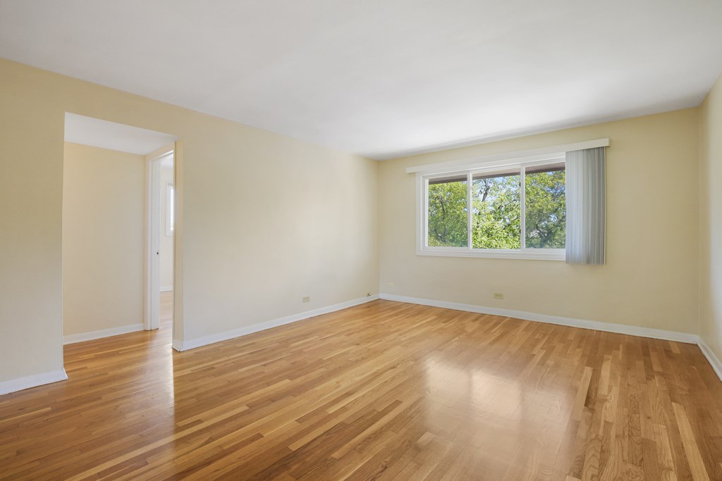 an empty living room with wood floors and a window