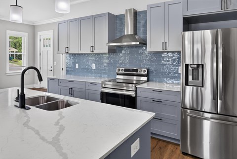 A modern kitchen with a stainless steel refrigerator and a marble countertop.