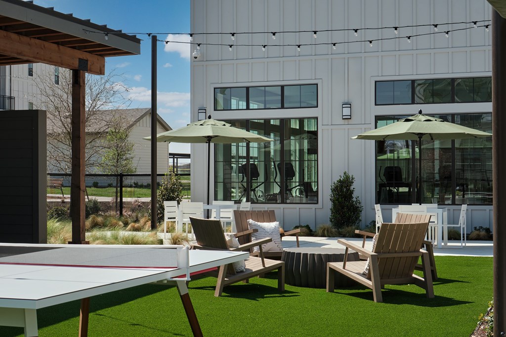 A table and chairs are set up on a lawn in front of a building.