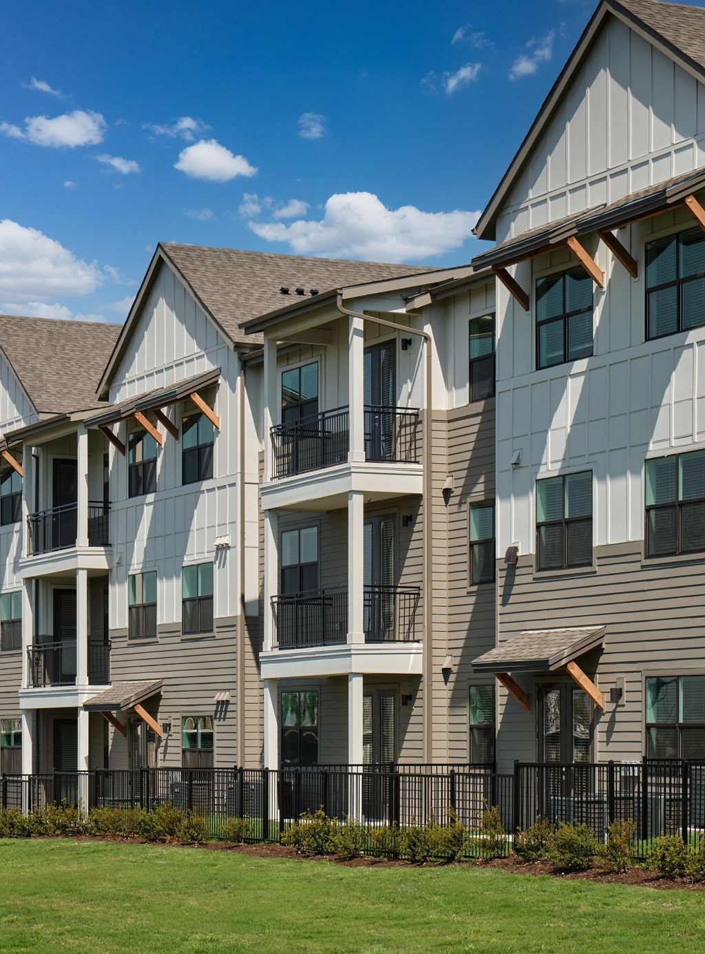 A row of modern townhouses with balconies and black railings.