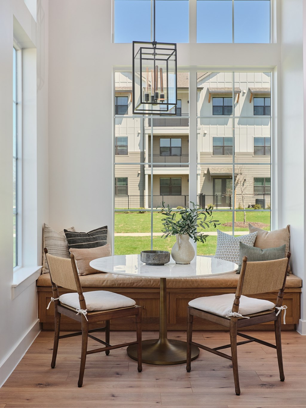 A dining table with two chairs in front of a large window with a view of a building outside.