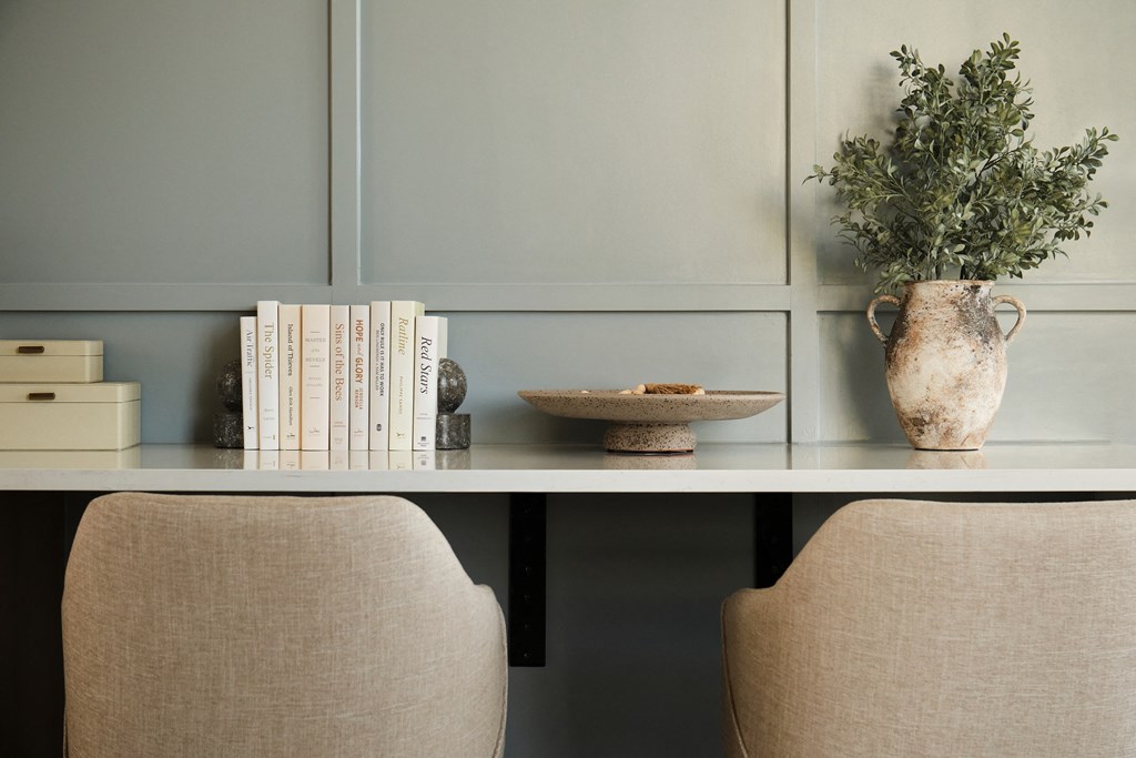 Two chairs sit on either side of a table with a plant and books on it.