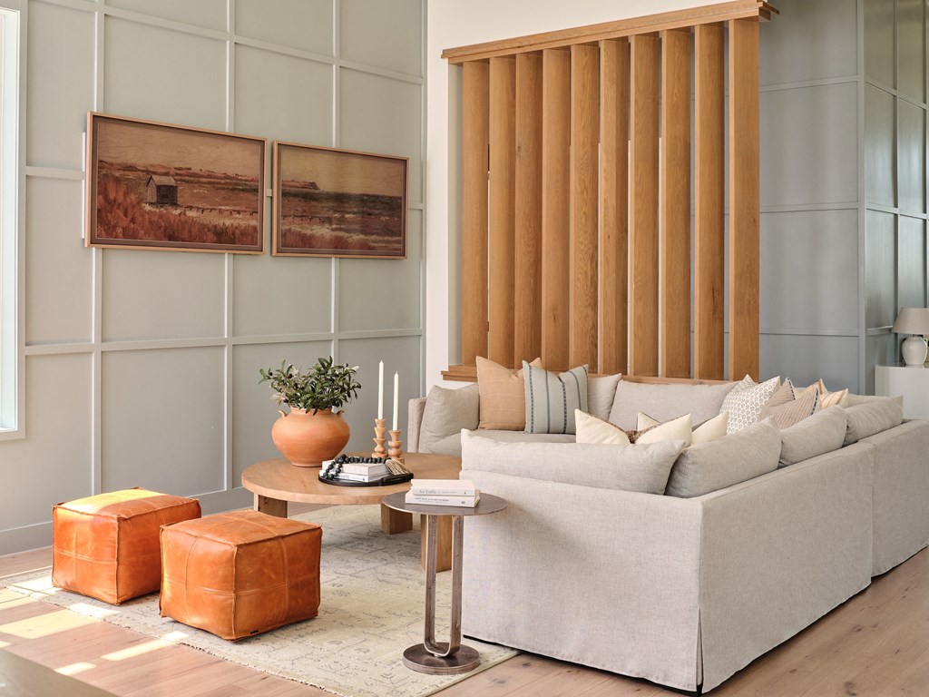 A living room with a white couch, a wooden coffee table, and two orange ottomans.