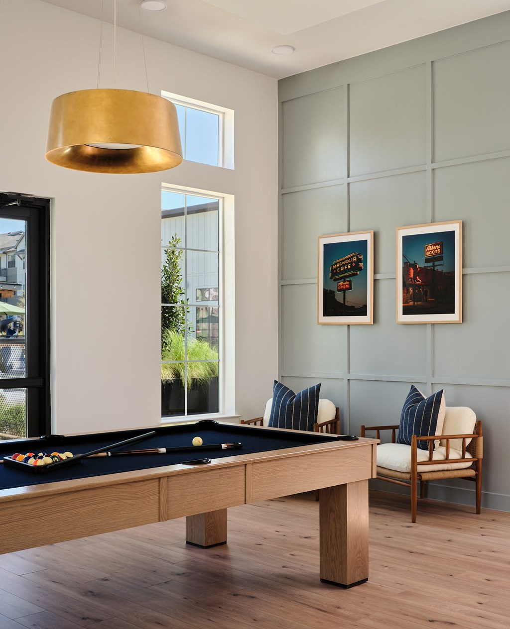 A pool table with a chair and two pictures on the wall.