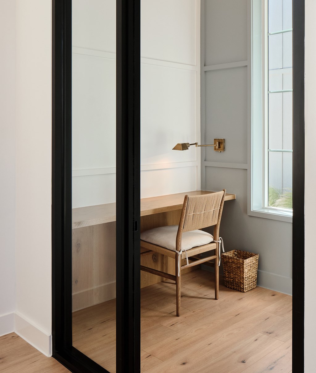 A chair sits in front of a desk with a lamp on it.