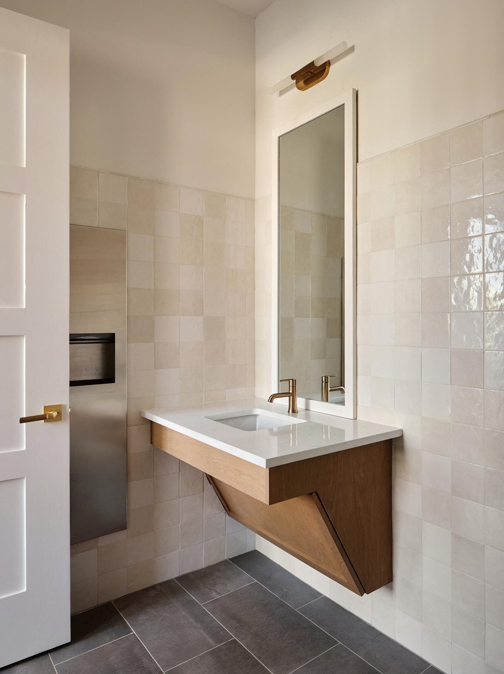 A modern bathroom with a wooden vanity and a large mirror.