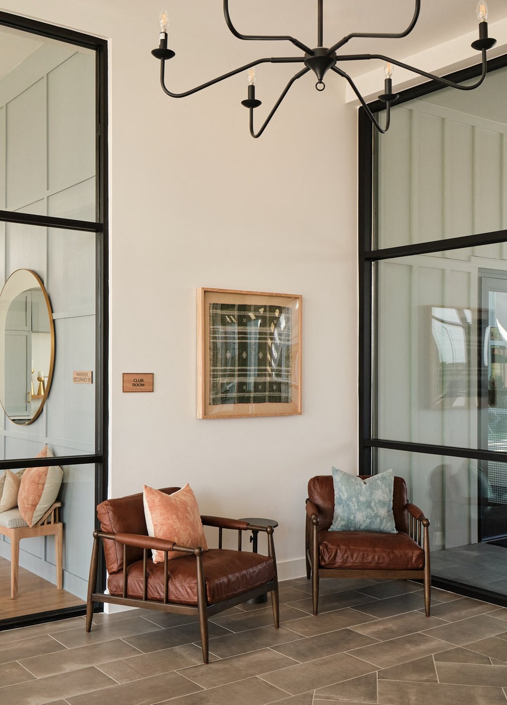Two brown leather chairs with cushions are placed in a room with a chandelier.
