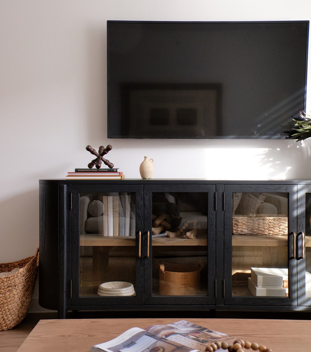A black cabinet with glass doors and a mirror above it.