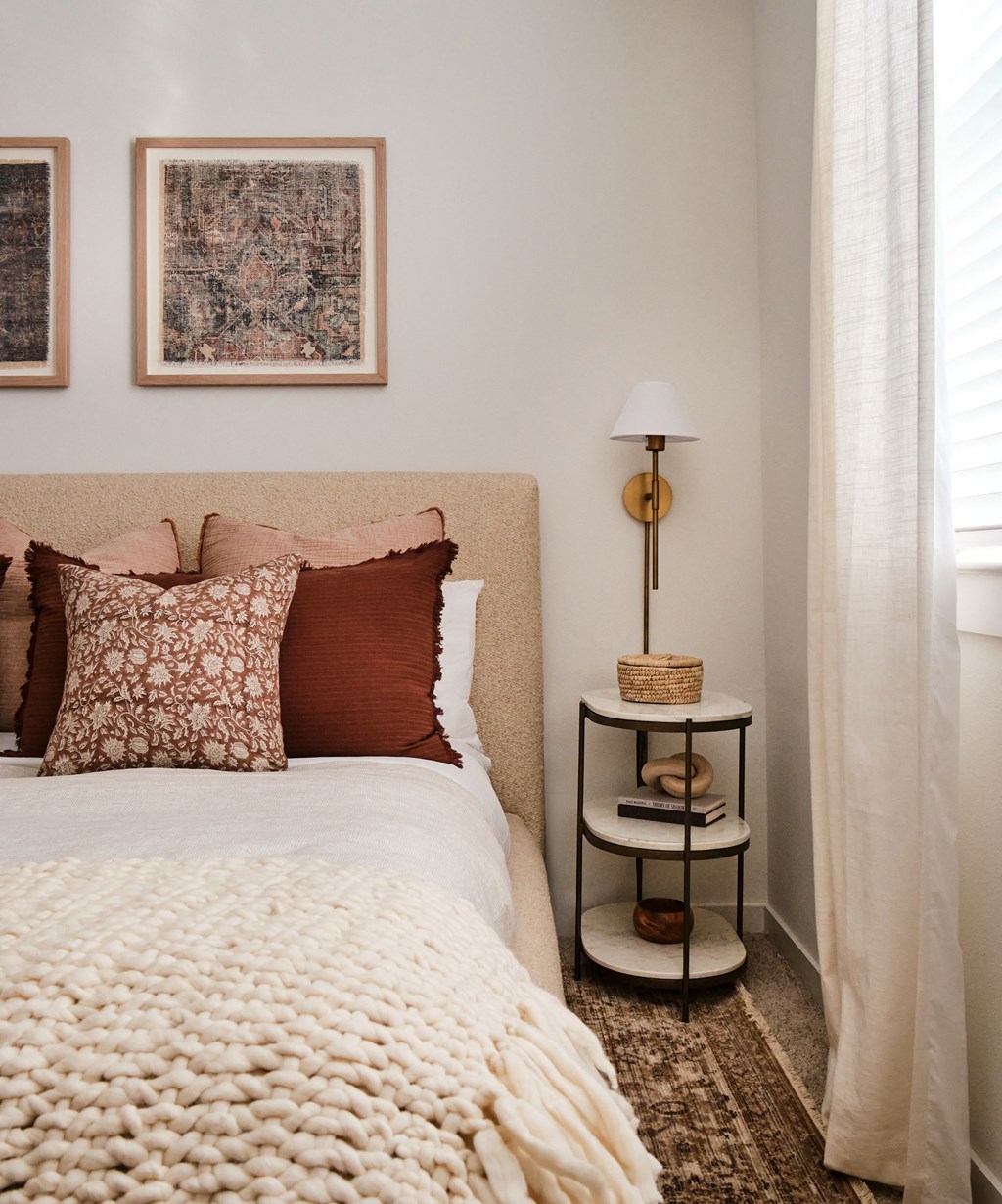 A bedroom with a bed, a lamp, and a basket on a side table.