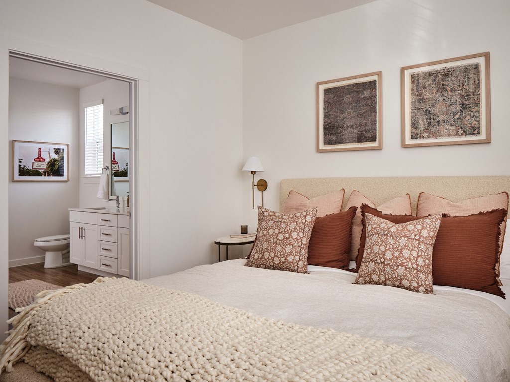 A bedroom with a bed, nightstand, and two wall hangings.