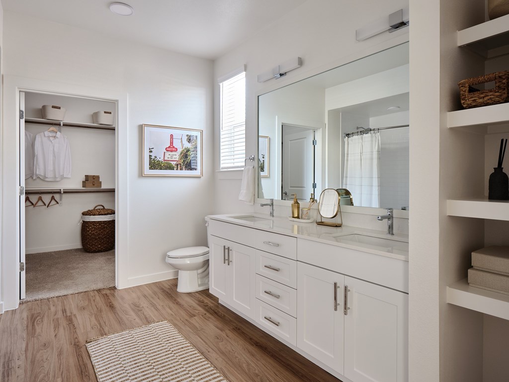 A white bathroom with a toilet, sink, and mirror.