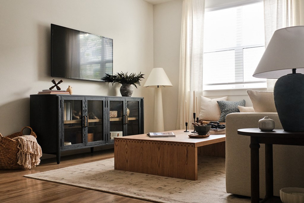 A living room with a dark cabinet, a wooden coffee table, and a large lamp.