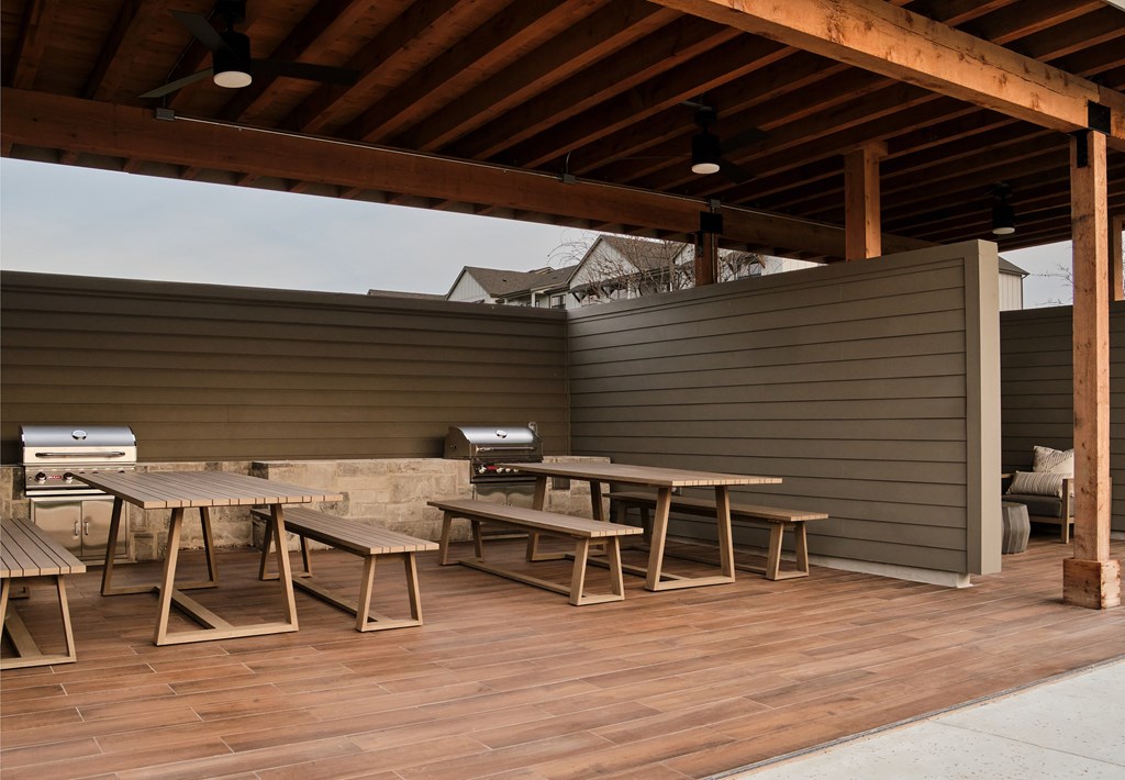 A wooden deck with a table and chairs under a roof.