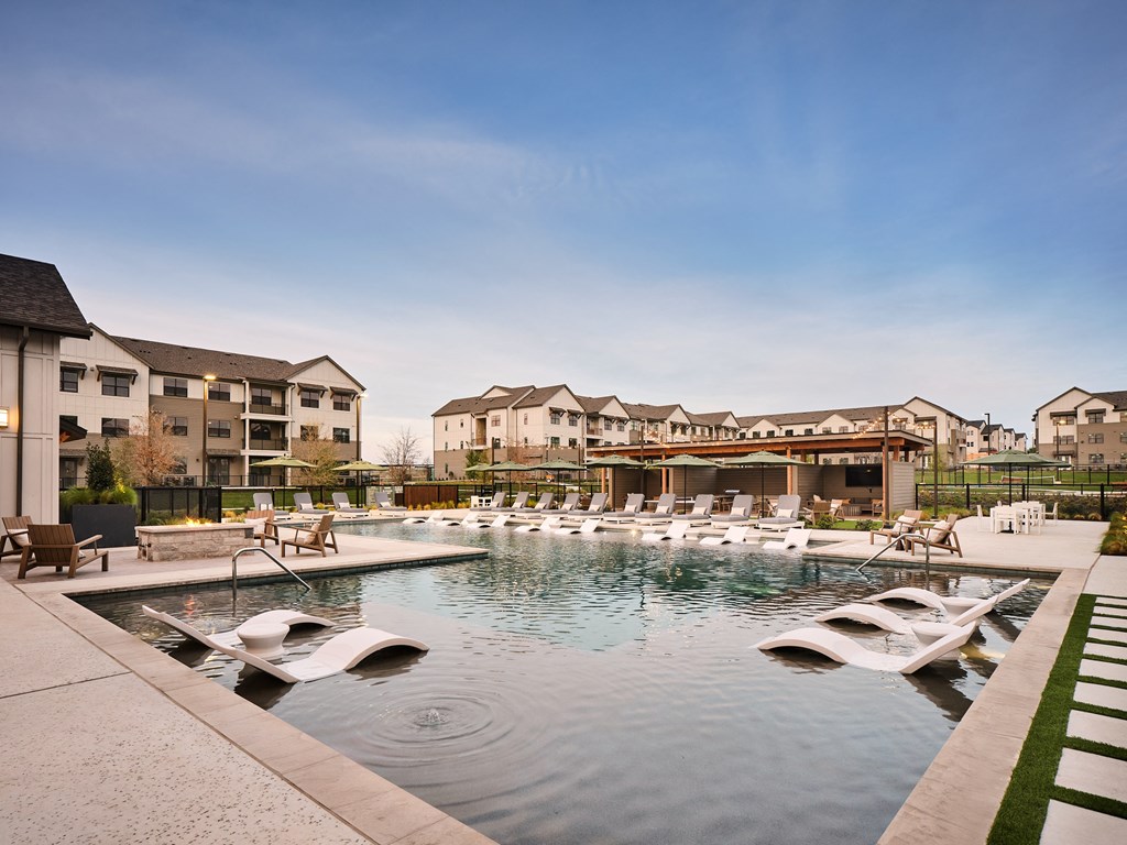 A large swimming pool with lounge chairs and a building in the background.
