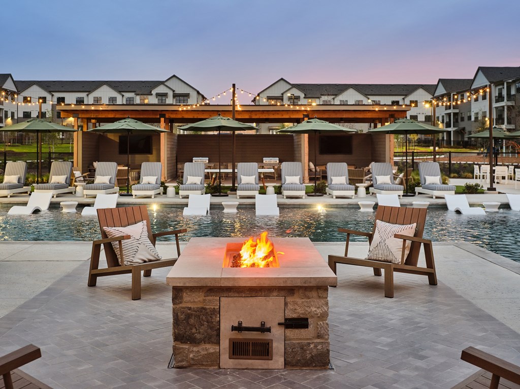 A fire pit sits in the middle of a pool surrounded by chairs.