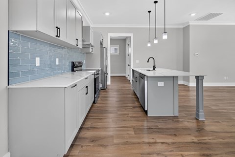 A kitchen with white cabinets and a blue tile backsplash.